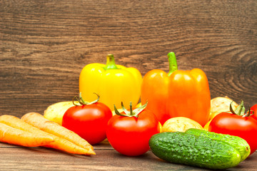 tomatoes, cucumbers, carrots and potatoes on wooden background