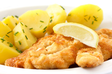 Golden fried schnitzel with boiled potatoes, chives and lemon.