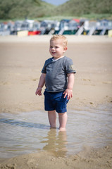 Fototapeta na wymiar little boy splashes in a pool on the beach