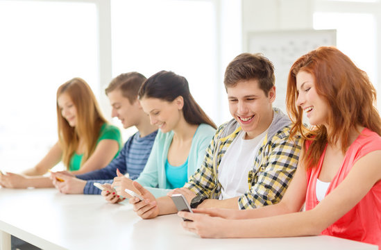 smiling students with smartphones at school