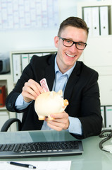 junger mann wirft geld ins sparschwein