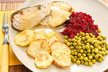 Portion of roast turkey breast in herbs with baked potatoes, bee