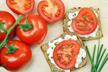 Sandwich with cottage cheese and tomato with chives on wood back