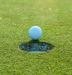 Golf Ball Rests at Edge of Hole Before Falling In