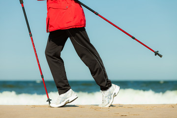 Fototapeta na wymiar Nordic walking. Female legs hiking on the beach.