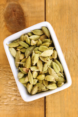 green cardamom in white bowl on wooden background close-up