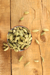 green cardamom in ceramical bowl on wooden background close-up