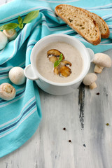 Mushroom soup in white pot, on napkin,  on wooden background
