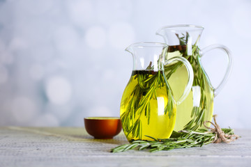 Essential Oil with rosemary in glass jug, on light background