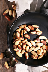 Tasty brasil nuts in pan on wooden background