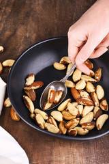 Tasty brasil nuts in pan on wooden background
