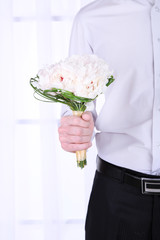 Man holding wedding bouquet on light background
