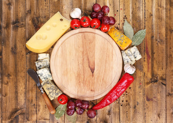 Different types of cheese with empty board on table close-up