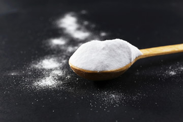 Spoon of baking soda on black background