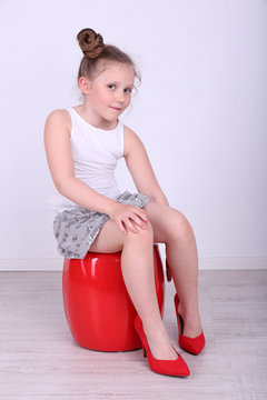 Beautiful small girl in big shoes sitting