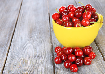 Sweet cherries in mug on wooden background