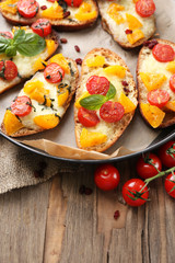 Tasty bruschetta with tomatoes on pan, on old wooden table