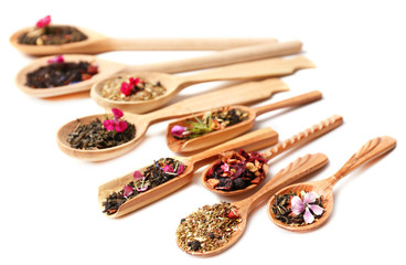 Assortment of dry tea in wooden spoons,  isolated on white