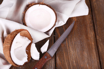 Broken coconut with knife and napkin on wooden background