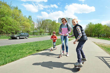 Family riding a skateboard and scooter