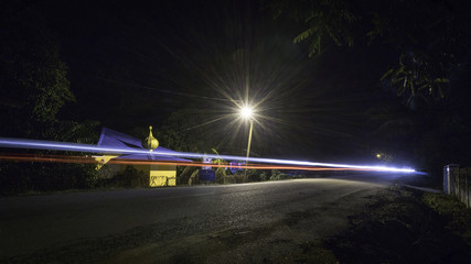Road at night with car light trail in rural Malaysia