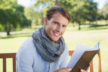 Fototapeta premium Stylish young man holding journal smiling at camera