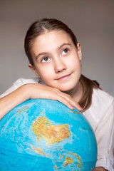 Dreaming smiling girl with blue globe. Childhood.