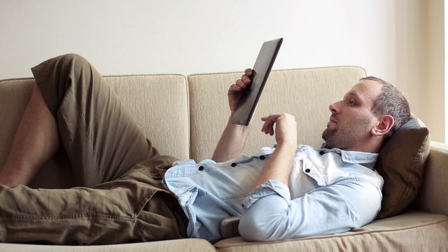 Young man with tablet computer on sofa at home