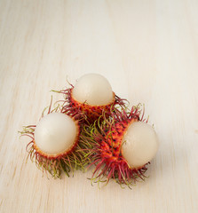 Rambutan fruit with red shell on wood background