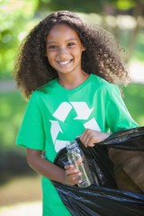 Young environmental activist smiling at the camera picking up tr