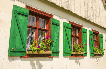 Windows, green shutters, flowers in wooden rural house, Europe