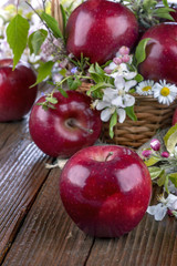 apples in a basket with flowers on wooden table