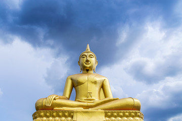 Obraz premium big golden buddha statue sitting on blue sky background