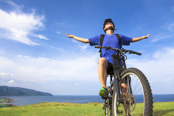 young man sitting on a  mountain bike and open arms to relaxing