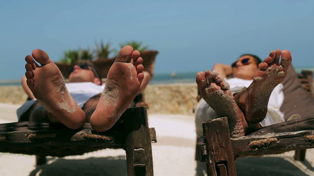 Couple resting on sunbeds, steadycam shot