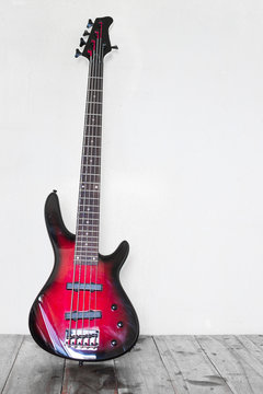 Red electric bass guitar leaning on wall and standing on table