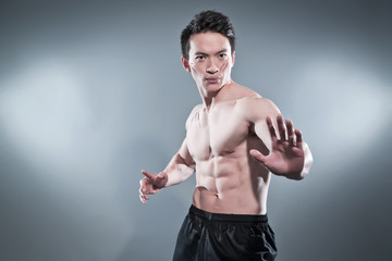 Muscled asian kung fu man in action pose. Blood stripes on his c