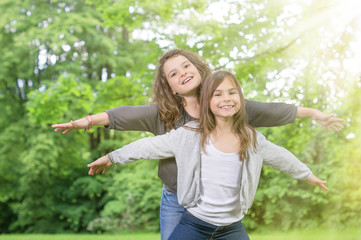Zwei Mädchen spielen Flieger im Park