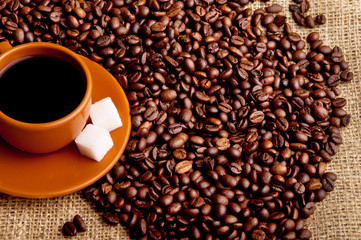 Cup of coffee with refined sugar and coffee beans.