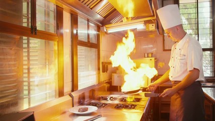 Chef cooking, preparing food, cook in restaurant kitchen