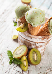 Kiwi fresh ice cream scoops in cones on wood