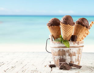Chocolate ice cream scoops in cones with beach
