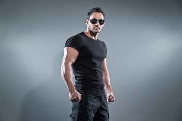 Combat muscled action hero man wearing black t-shirt with pants