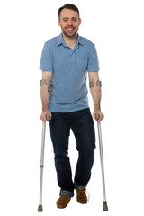 Smiling young man using crutches