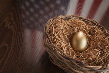 Golden Egg in Nest with American Flag Reflection on Table