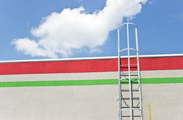 Safety metal ladder to the roof over blue sky