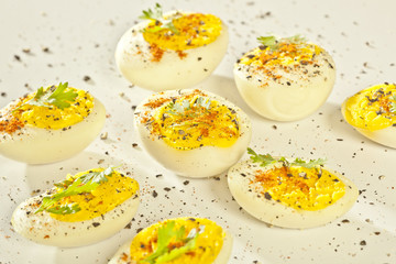 Hard boiled eggs, sliced in halves on white background