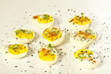 Hard boiled eggs, sliced in halves on white background