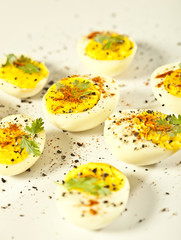 Hard boiled eggs, sliced in halves on white background