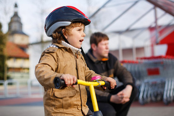 Little toddler boy with bicycle and his father in the city